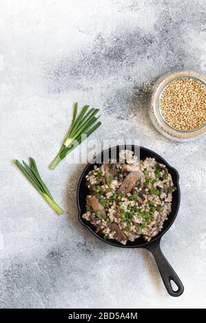 Sarrasin aux champignons et oignons verts. Un plat latéral ou un porridge traditionnel d'Europe de l'est. Plat végétarien sain. Servi dans une poêle Banque D'Images