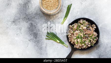 Sarrasin aux champignons et oignons verts. Un plat latéral ou un porridge traditionnel d'Europe de l'est. Plat végétarien sain. Servi dans une poêle Banque D'Images