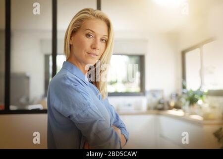 Attractive blonde woman standing with arms crossed Banque D'Images