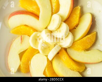 Ingrédients de salade de fruits de segments d'orange tranches de pomme couvertes de jus de citron et de tranches de banane dans un grand bol d'en haut Banque D'Images