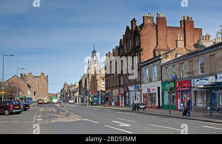 Portobello, Édimbourg, Écosse, Royaume-Uni. 7 avril 2020. Eeerily calme Portobello High Street avec des résidents qui ont pris en compte le coronavirus Lockdown du Royaume-Uni, il y avait très peu de personnes dehors et à peu près. Une femme dans la rue High Street attend avec optimisme un bus et juste derrière elle le poissonnier local John Williamson ouvert pour les affaires. Banque D'Images