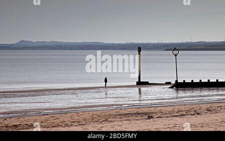 Portobello, Édimbourg, Écosse, Royaume-Uni. 7 avril 2020. Eerily Quiet Beach avec un homme isolé marchant le long du rivage avec des résidents qui ont pris en compte le coronavirus Lockdown du Royaume-Uni, il y avait très peu de personnes dehors et autour. Banque D'Images