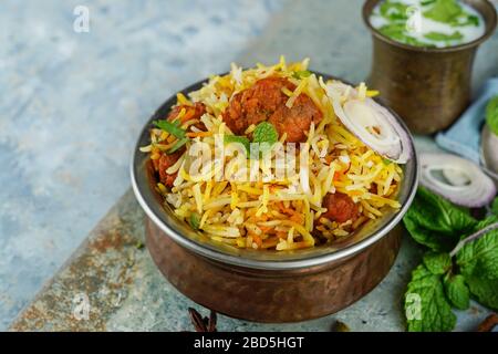 Tikka Biryani, poulet maison, servi dans un récipient traditionnel en laiton avec sauce au yaourt, foyer sélectif Banque D'Images