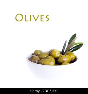 Olives vertes dans un bol en céramique blanc avec branche olive. Isolé sur blanc avec espace pour le texte. Banque D'Images