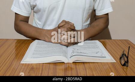 Un homme tenant ses mains sur un livre Saint ouvert. Concept de prière. Banque D'Images