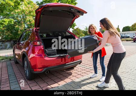 Les filles ont placé la valise de voyage dans le grand coffre de la voiture Banque D'Images