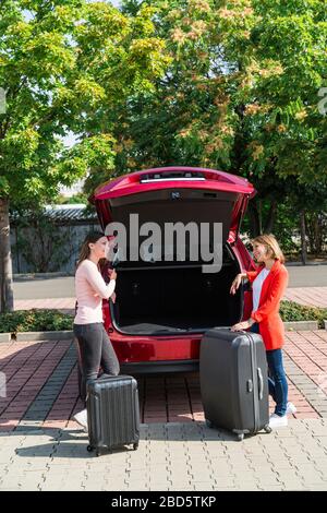 Deux filles ont apporté des valises pour ouvrir le coffre de la voiture Banque D'Images