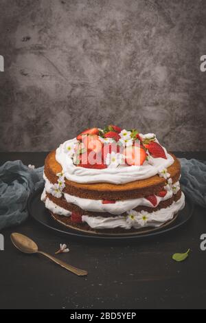 Gâteau aux fraises, gâteau aux fraises et crème aigre frais sur un comptoir de cuisine sombre. Banque D'Images