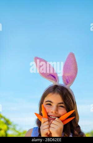 Portrait d'une jolie petite fille de lapin avec des carottes appréciant Pâques, ayant le jardinage amusant dans la cour sur une bonne journée ensoleillée Banque D'Images