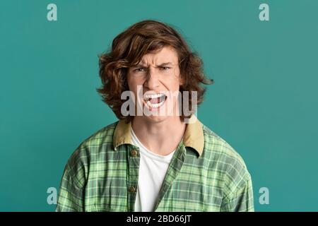 Exprimer la colère. Jeune gars à l'expression furieuse du visage sur fond de couleur Banque D'Images