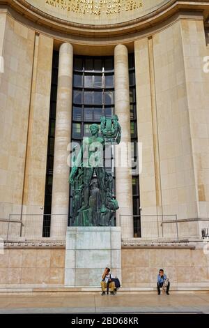 Deux visiteurs masculins s'assoient devant l'une des statues grecques du complexe Trocadéro dans le centre de Paris. Banque D'Images