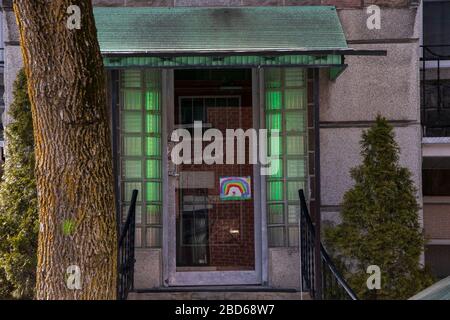 4 avril 2020 - Montréal, QC, Canada :Rainbow s'étirant dans une fenêtre de porte sur une façade de bâtiment d'appartement pendant la pandémie de Coronavirus (COVID-19), Rosemont Banque D'Images