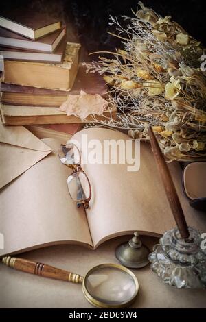 Lunettes dans une lettre non écrite, vieux stylo dans un inkwell pour un manuscrit. Livres et bouquet de fleurs séchées. Concept de nostalgie vintage Banque D'Images