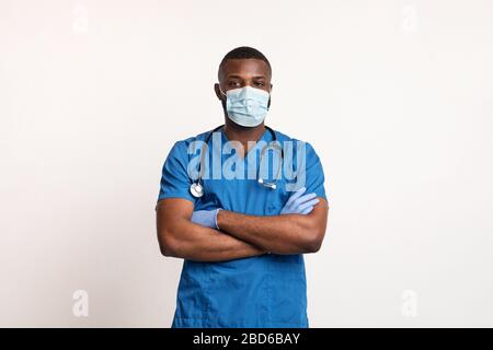 Médecin noir confiant dans le masque de visage et gants sur blanc Banque D'Images