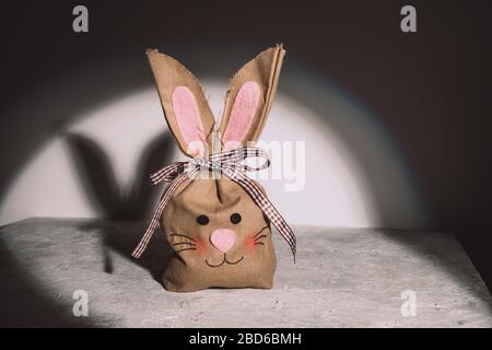 Œufs de Pâques dans un sac en lin d'artisanat écologique sur un fond gris grunge avec une lumière ciblée. Banque D'Images