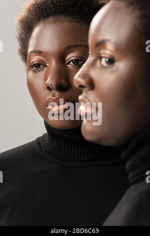 portrait d'amis afro-américains dans des moutartinades noires isolées sur le gris Banque D'Images