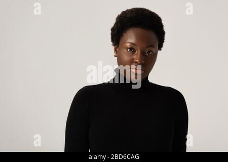 jolie femme afro-américaine en turtleneck noir isolée sur gris Banque D'Images