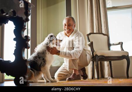 Portrait d'un homme souriant et mûr qui pettait son chien. Banque D'Images