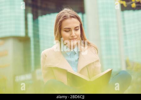 Étudiant étudiant étudiant en extérieur sur le campus. Gros plan femme d'affaires souriant livre de lecture, contrat assis sur herbe pré dans le parc isolé bureau bui Banque D'Images