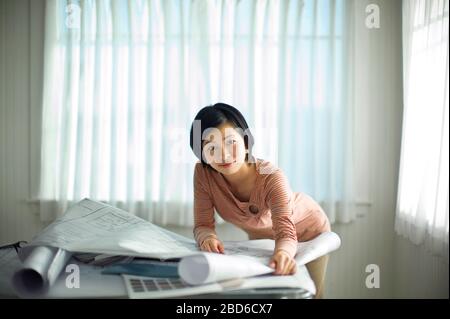 Portrait d'une jeune femme regardant des échantillons de couleur et des plans d'amélioration à la maison. Banque D'Images