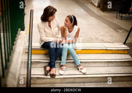 Femme et sa petite-fille assise sur les marches à une station de train. Banque D'Images