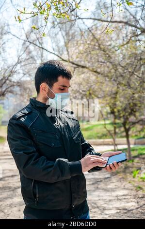 COVID-19. Young Man Outdoor désinfecte Phone Antibactérien Napkin. Concept de coronavirus. Banque D'Images