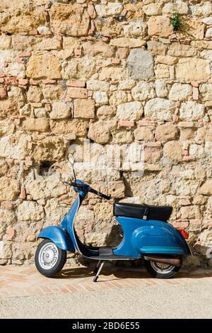 Scooter bleu près du mur de pierre dans une vieille ville en Toscane, Italie Banque D'Images