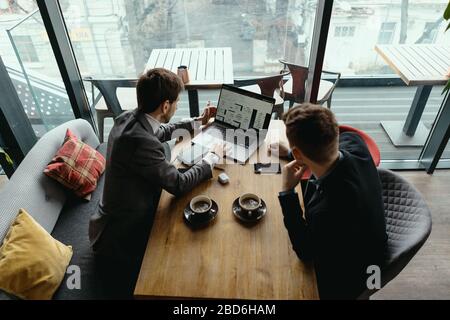 Deux hommes d'affaires parlent de nouvelles opportunités assis avec un ordinateur portable au bureau, projet de planification, considérant l'offre d'affaires, partager des idées Banque D'Images