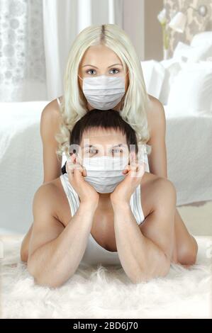 joli couple dans le masque médical, se trouve sur le sol à la maison, concept coronavirus covid-19 épidémie Banque D'Images