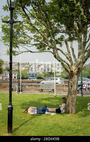 Amies profitant du soleil dans le parc de la ville près du port de Kinsale lors d'une chaude journée ensoleillée d'été à Kinsale, comté de Cork, Irlande Banque D'Images