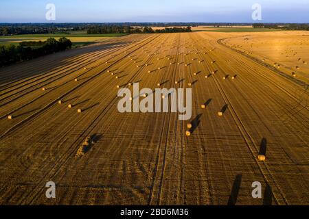 Piencourt, Normandie, France. Vue aérienne des champs de paille avec balles en France rurale au coucher du soleil Banque D'Images