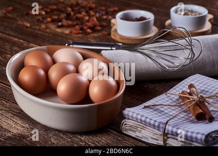 Vue rapprochée d'un bol d'œufs de poule, d'un chiffon et d'un fouet. Raisins secs sur la table de bois ancienne avec de l'espace pour le texte. Banque D'Images