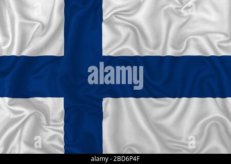 Drapeau finlandais sur fond de tissu en soie ondulé. Banque D'Images