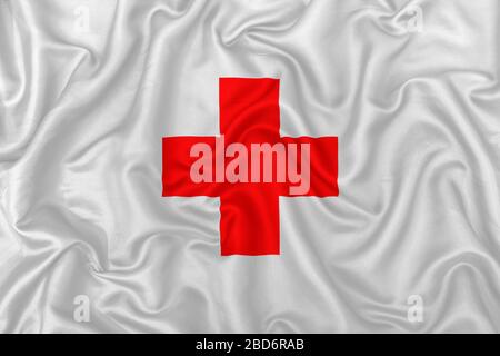 Croix médicale rouge sur un fond de texture en soie satin ondulé. Banque D'Images