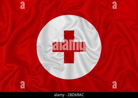Croix médicale rouge sur un fond de texture en soie satin ondulé. Banque D'Images