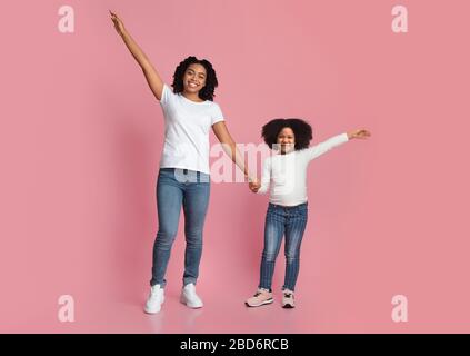 Joyeux maman noire Smiling et fille posant avec des mains levées Banque D'Images