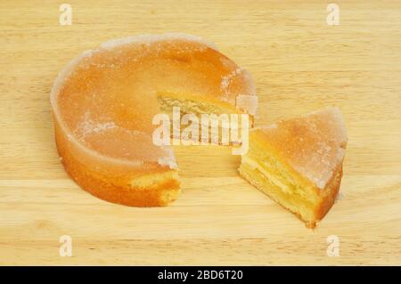 Arrosez de citron un gâteau éponge avec une tranche coupée sur une planche à découper en bois Banque D'Images