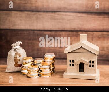 Un concept de propriété de logement avec une maison et des piles d'argent représentant les économies de famille et le coût du logement, des factures, la vente, l'achat avec l'espace de copie Banque D'Images