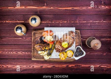 Délicieux bifteck grillé avec assortiment de légumes rôtis et maïs. Il y a un moulin à poivre et une sauce. Vue de dessus Banque D'Images