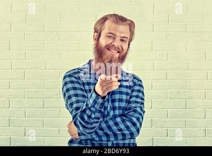 Portrait d'un homme-chemise bleu souriant et décontracté regardant vous montrer appareil photo geste isolé mur de briques blanches arrière-plan. Image jaune, h Banque D'Images