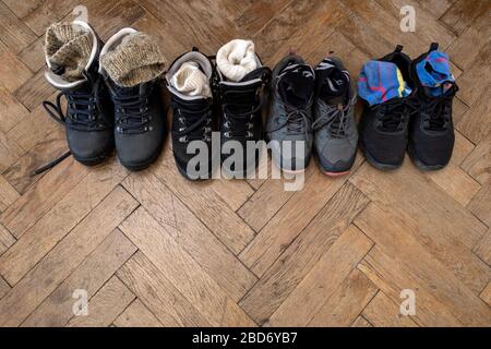 Quatre paires de bottes pour la randonnée sur le sol en bois. Vue de dessus des chaussures pour le tourisme. Espace de copie. Banque D'Images