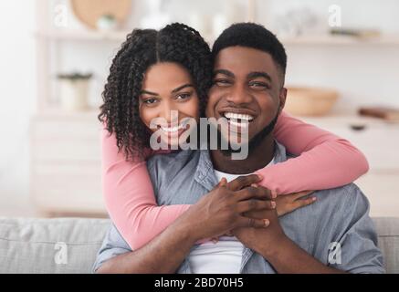Un couple afro-américain affectueux embrassant à la maison et regardant l'appareil photo Banque D'Images