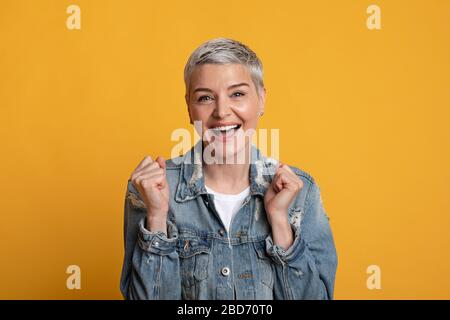 Femme mûre émotionnelle criant et célébrant le succès avec des poings serrés Banque D'Images