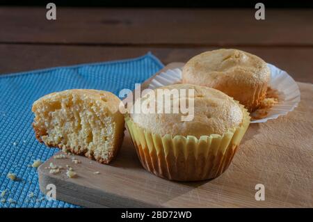 Cornmeal cupcakes sur un vieux tableau de découpe, cupcakes s'émietent sur une nappe bleue Banque D'Images