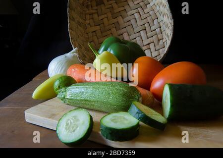 Légumes sur un tableau de découpe dans une cuisine mexicaine vue latérale avec un panier en arrière-plan et des tranches de concombre Banque D'Images