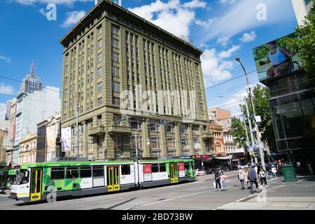 Melbourne, Australie - 9 mars 2020; Old London Stores Ltd bâtiment à travers l'intersection animée de la ville avec le tram passant par et les personnes portant le visage Banque D'Images