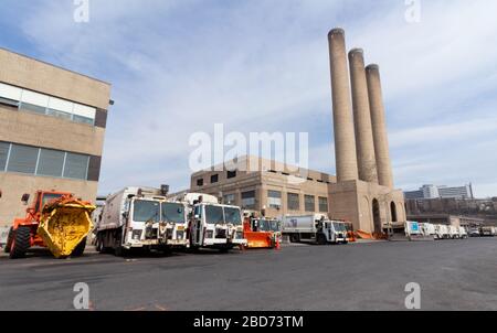 Divers types de camions sanitaires pour l'enlèvement des ordures et l'enlèvement de neige alignés dans un dépôt du Département de l'assainissement de la ville de New York Banque D'Images