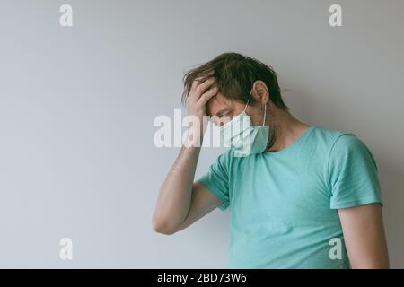 Homme avec masque ayant des maux de tête de migraine comme symptômes de Covid-19, portrait de homme avec infection virale pendant les pandémies Banque D'Images