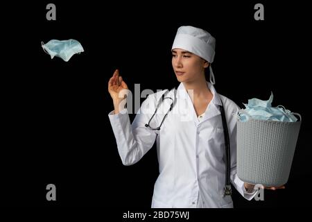 Le médecin tient un seau rempli de masques faciaux usagés, les jetant comme symbole de fin d'épidémie Banque D'Images