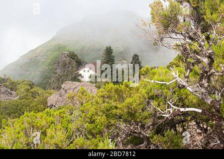 Une maison blanche avec un toit carrelé dans les montagnes parmi les nuages. Banque D'Images